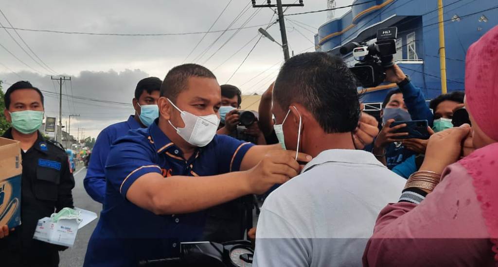 Ketua DPD Partai NasDem Tapteng, Bakhtiar Ahmad Sibarani Memakaikan Masker kepada Warga Disela-sela Pembagian Takjil di Depan Sekretariat Partai NasDem, Selasa sore 27 April 2021.