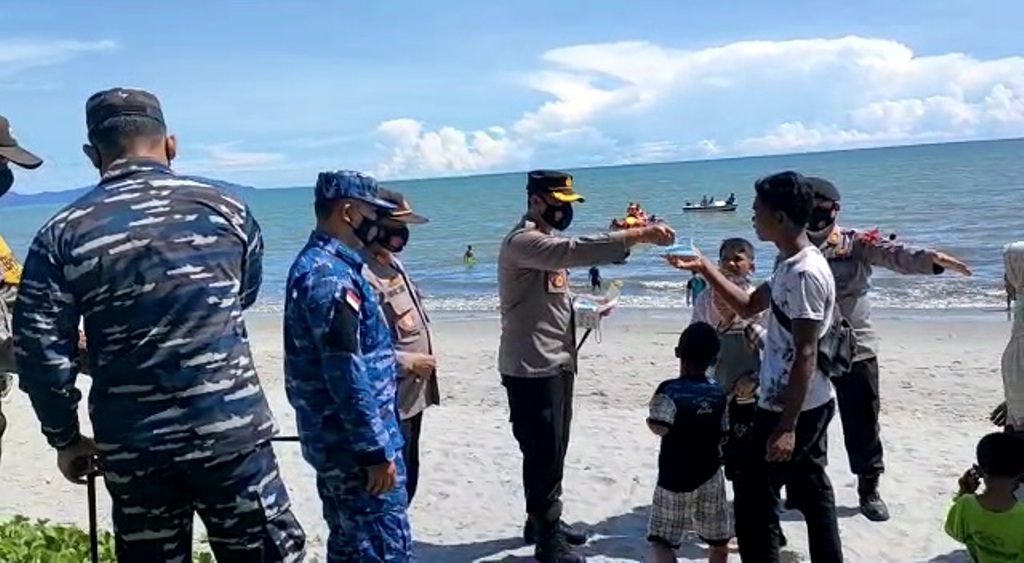 Kapolres Tapteng AKBP Nicolas Dedy Arifianto Membagikan Masker kepada Pengunjung Pantai.